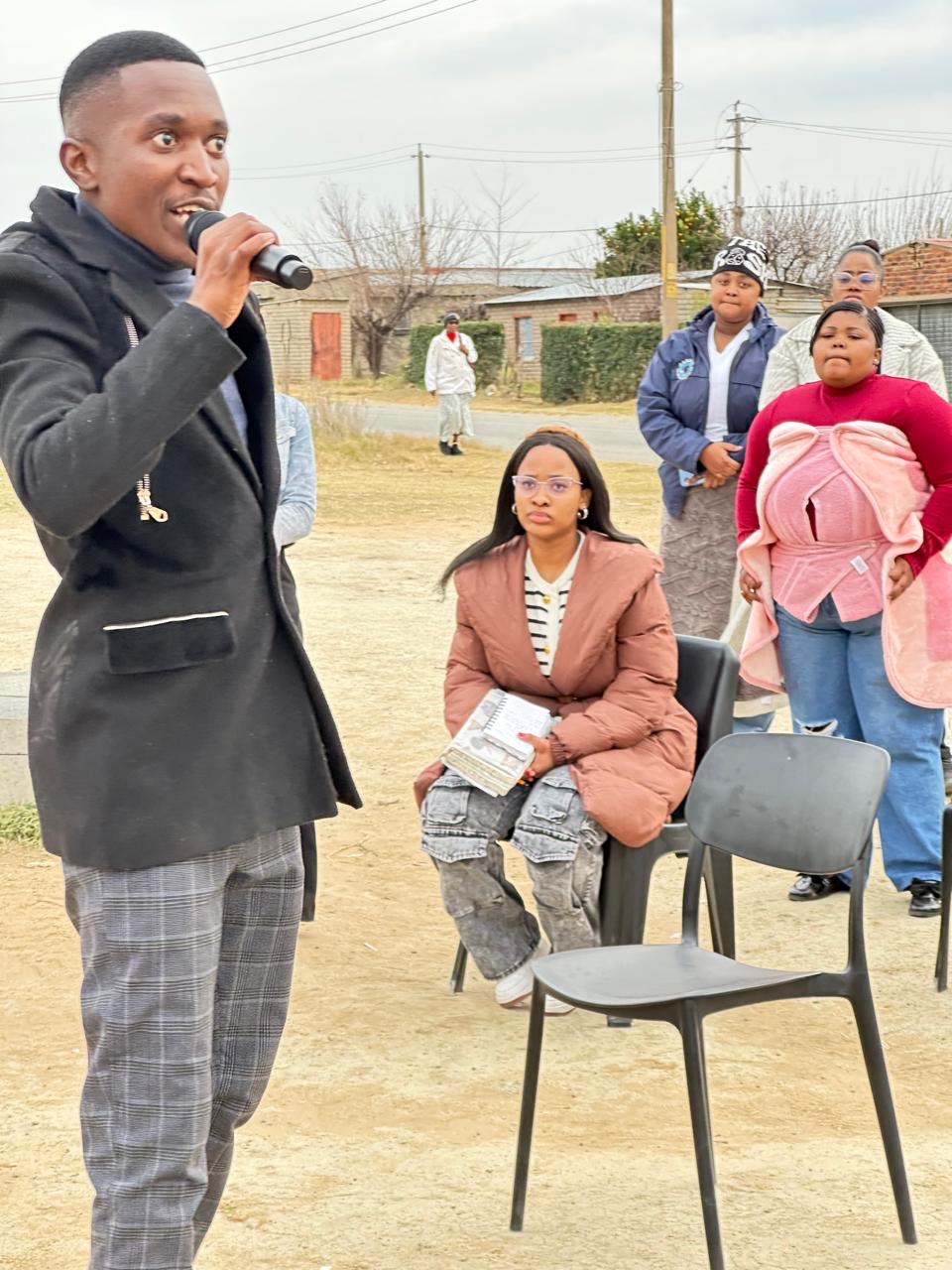 A young preacher speaking into a microphone at an open air service