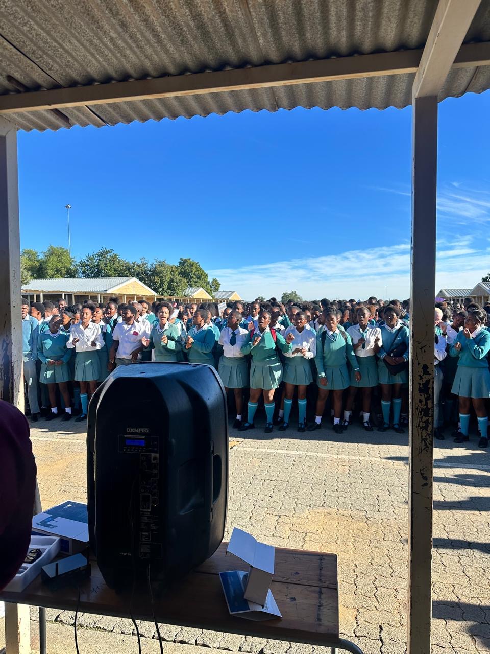Learners in school uniform gathered outdoors singing during an open air school visit