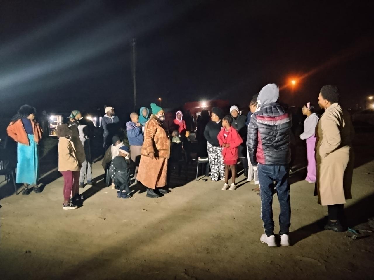 A crowd standing together at an open air gathering after dark