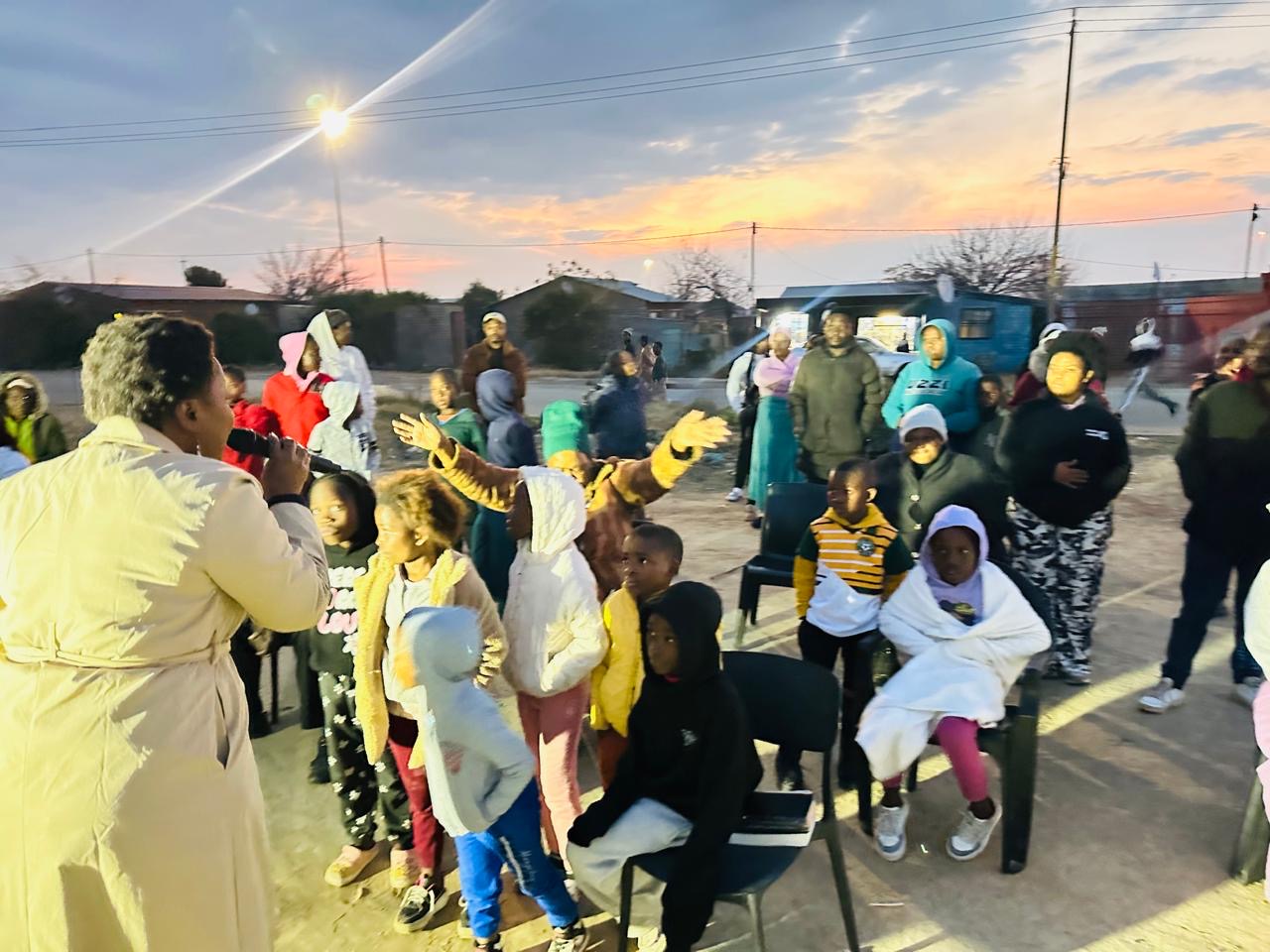 Children and adults worshipping with raised hands at sunrise in the street