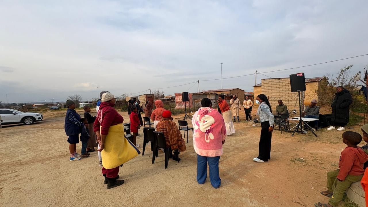 Community members standing in a circle listening during an open air service