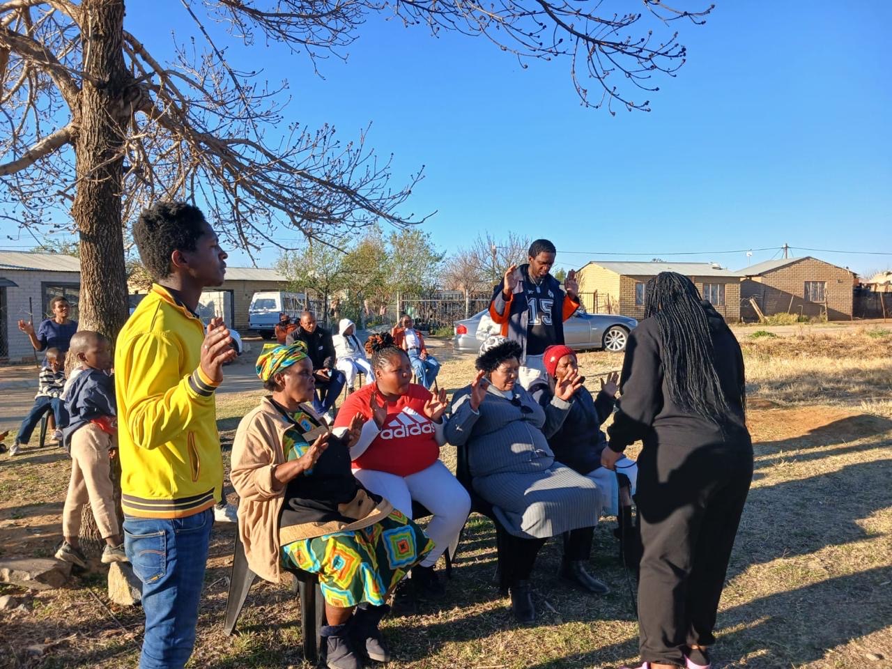 A group praying together with hands raised in a yard