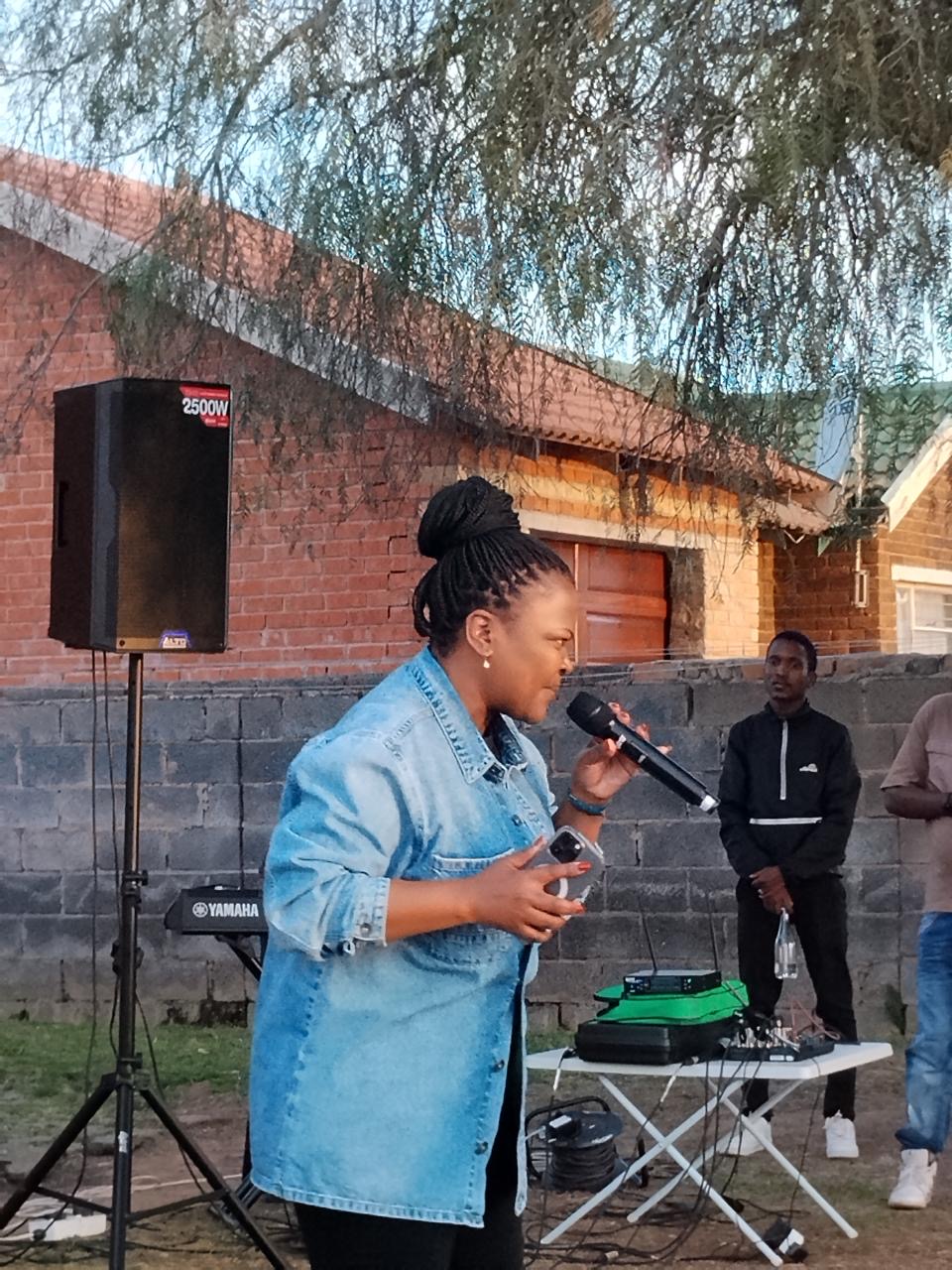 A woman leading worship with a microphone outdoors